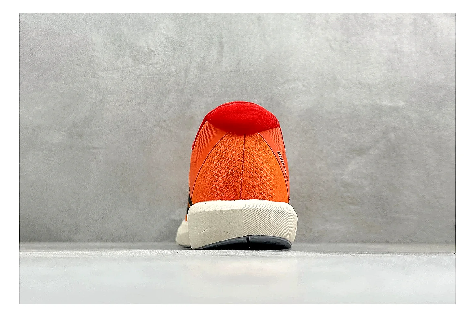 Adidas Adizero Orange Black QC reference photo showing orange runner upper, black three-stripe contrast, lightweight racing shape, and thin performance sole