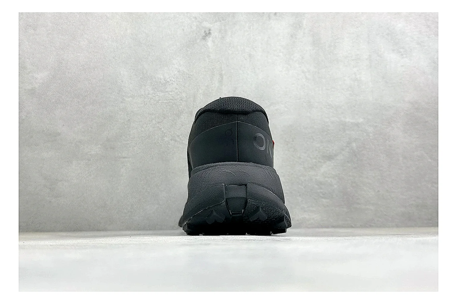 On Cloudmonster Triple Black QC reference photo showing triple black mesh upper, oversized CloudTec sole pods, tonal laces, and rounded runner shape