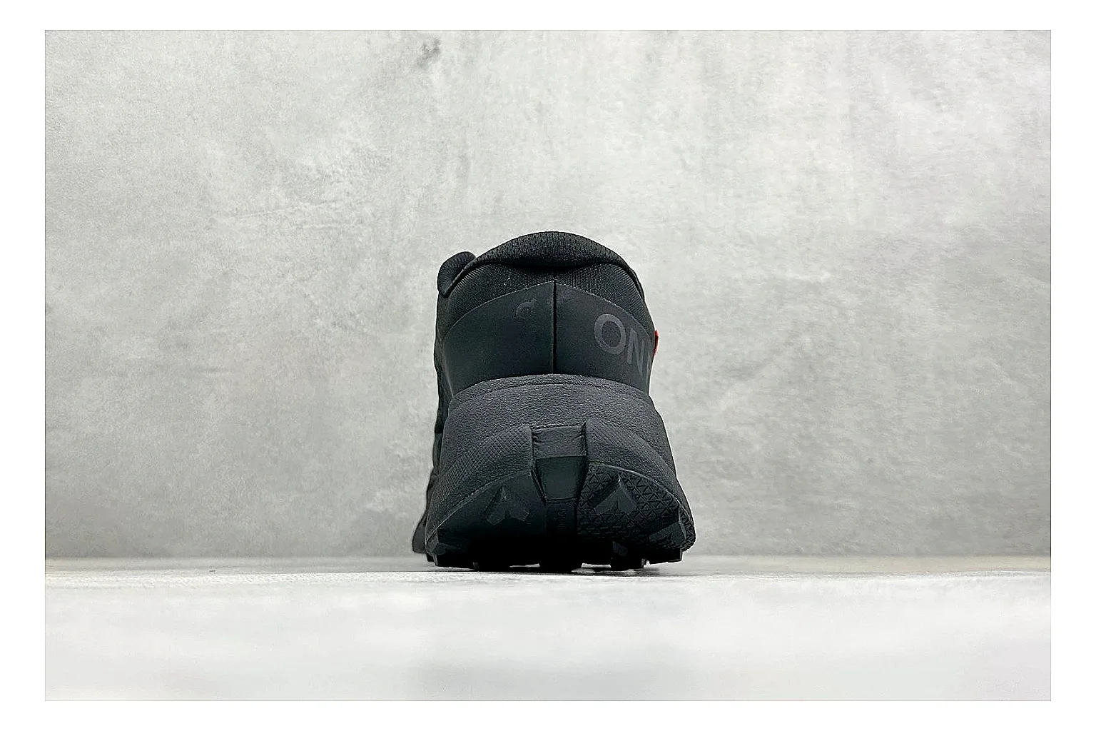 On Cloudmonster Triple Black QC reference photo showing triple black running upper, oversized CloudTec pod sole, tonal laces, and rounded performance shape