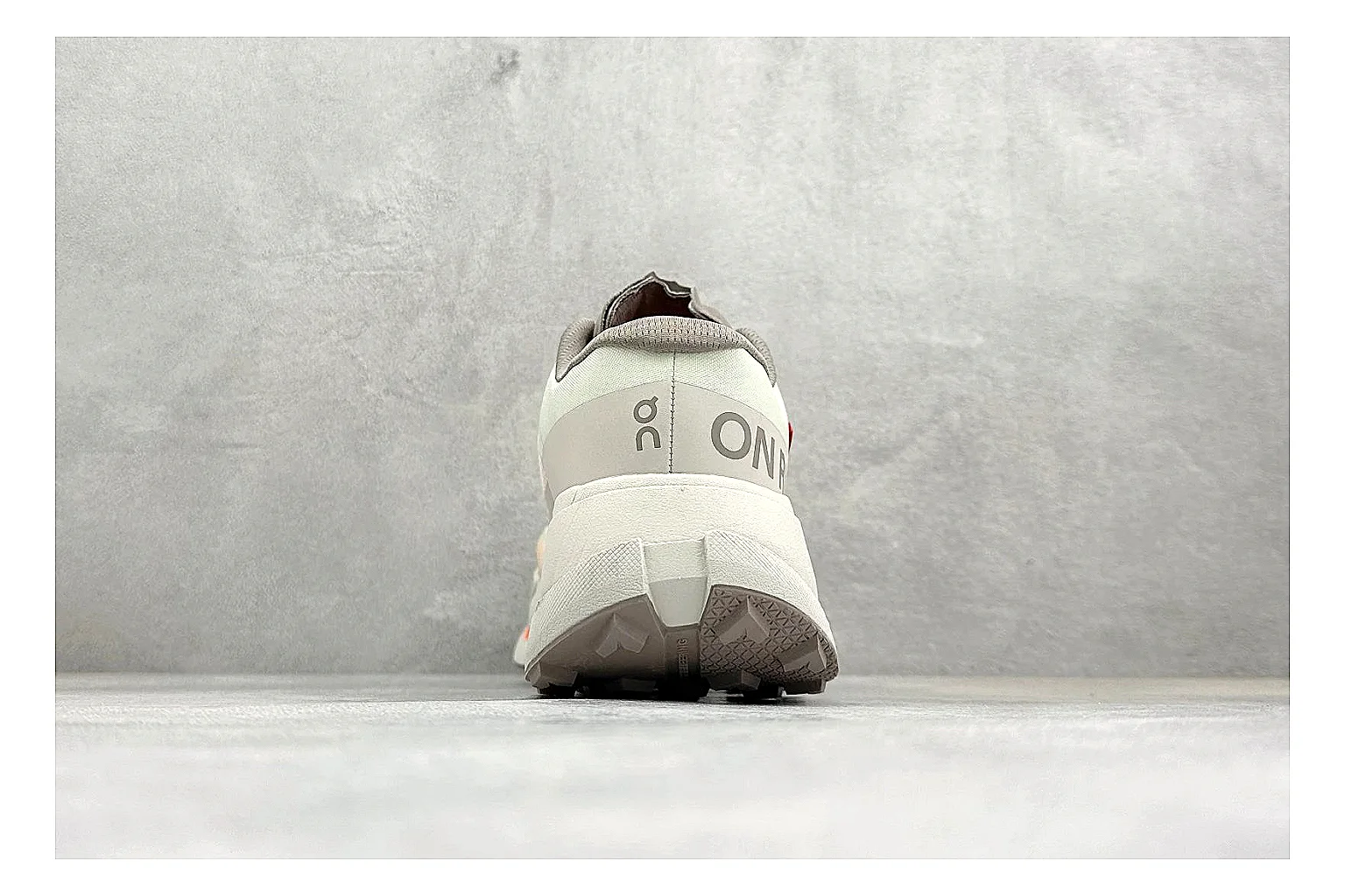 On Cloudmonster White Orange QC reference photo showing white running mesh, orange accent hits, oversized CloudTec sole pods, and a rounded runner silhouette